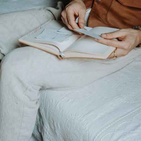man relaxing with open journal on bed